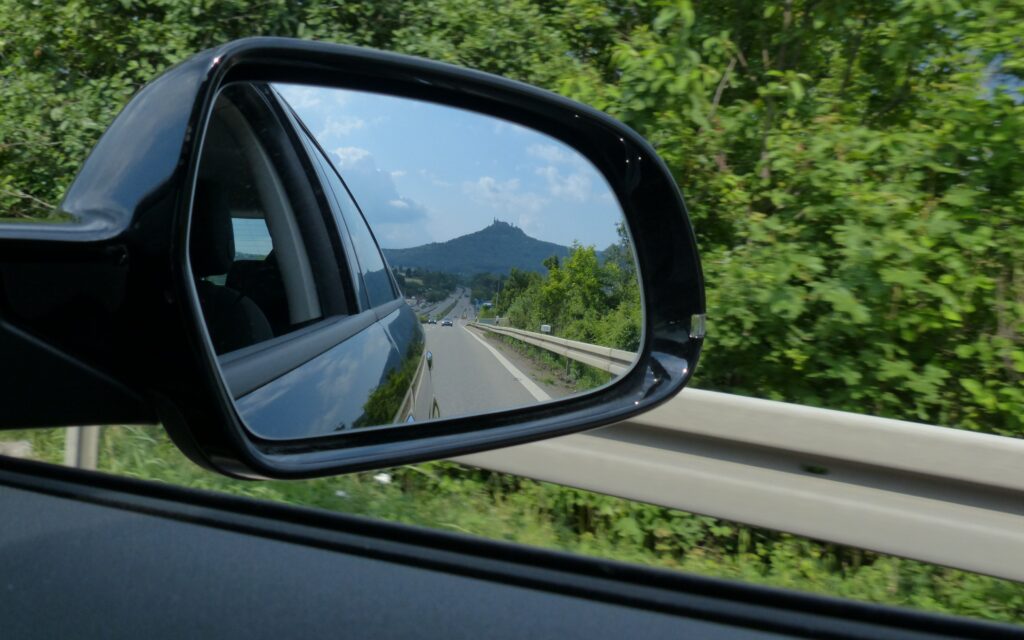 Reflet dans un rétroviseur extérieur de voiture sur l'autoroute s'éloignant dune montagne