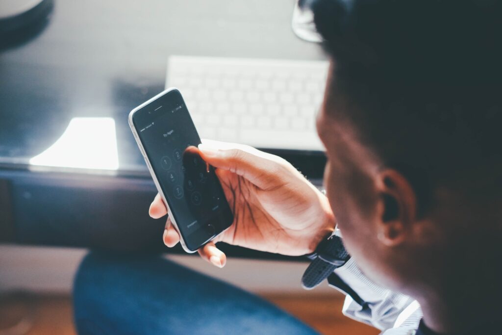 Vue par dessus l'épaule d'un homme en chemise assis et regardant son smartphone